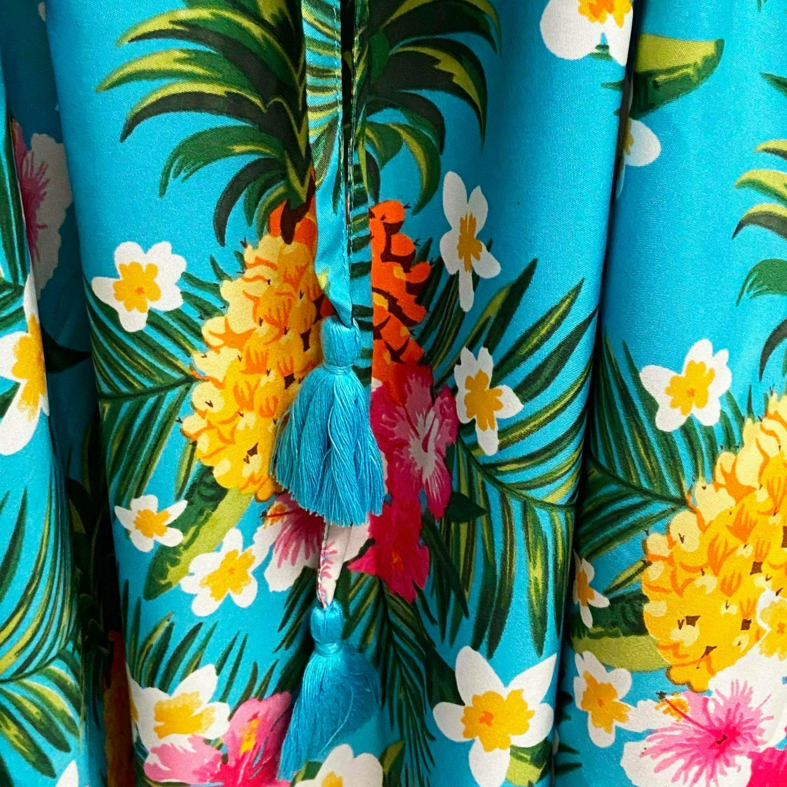 Repeating pattern tropical print with pineapples, frangipannis and palm fronds