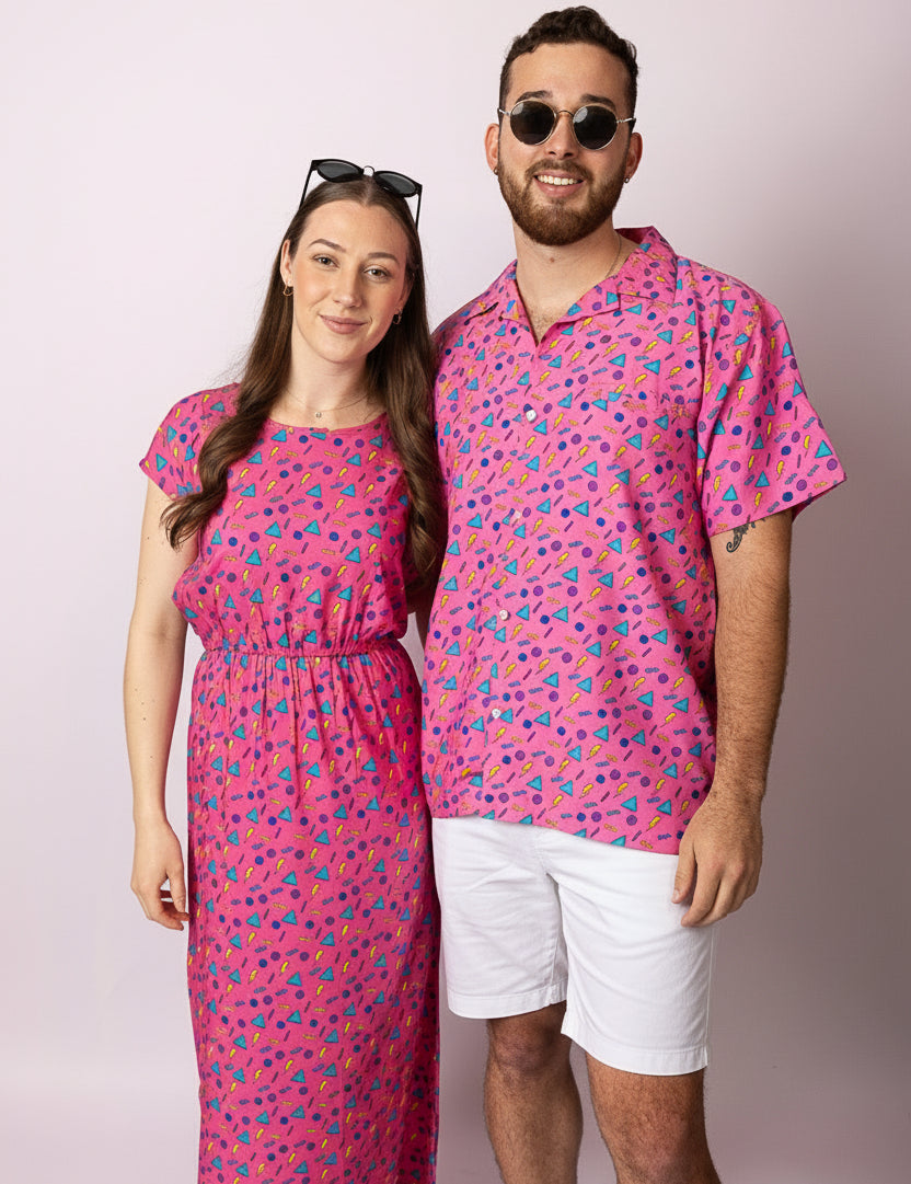 Two people wearing matching pink outfits with a pattern on a plain background