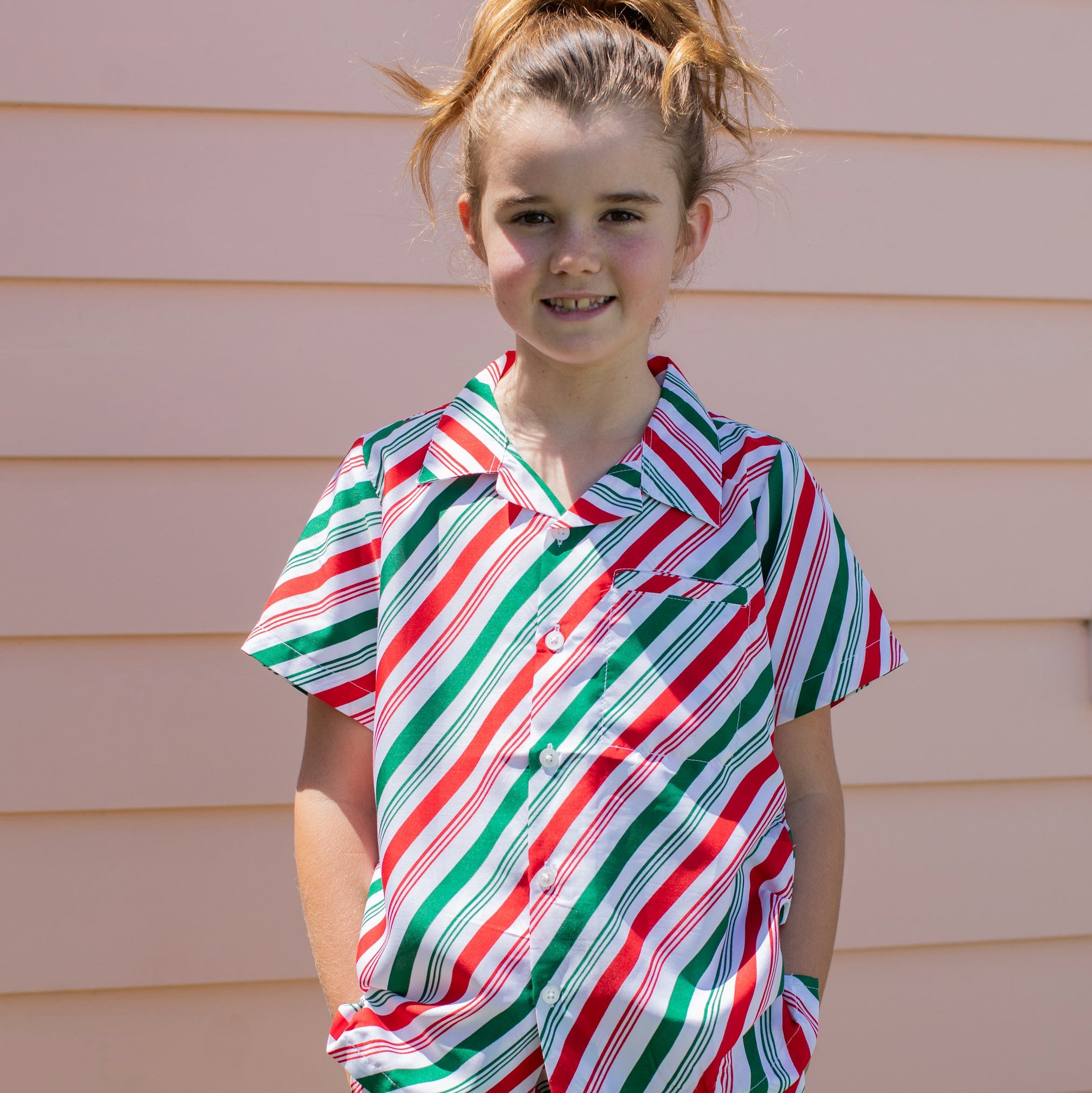 Jolly Stripe Christmas Kids Shirt features red, green, and white holiday stripes; festive tropical style. | Tropicool Clothing