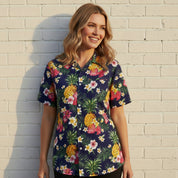 Smiling woman wearing the Aloha Navy Adult Shirt with a vibrant pineapple and hibiscus print, styled for a casual tropical look.
