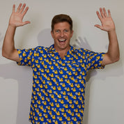 Man wearing a blue shirt with yellow duck pattern, standing against a plain background
