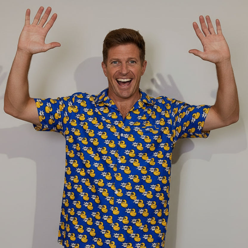 Man wearing a blue shirt with yellow duck pattern, standing against a plain background
