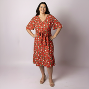 Full-length studio photo of a woman modelling the Alice Gingerbread Jest Christmas dress by Tropicool, featuring a red print with gingerbread and festive motifs