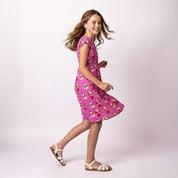 Side view of the Holly Santa Polka Pink Child Dress for kids, featuring bright pink Christmas print, comfortable elastic waist and lightweight summer fabric.