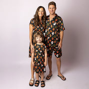 Family wearing matching Tropicool JingleVerse Christmas outfits, including the Alice adult dress, kids dress, and men’s shirt.