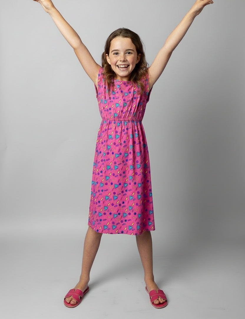 Young girl wearing a pink dress with retro vibe pattern on a white background