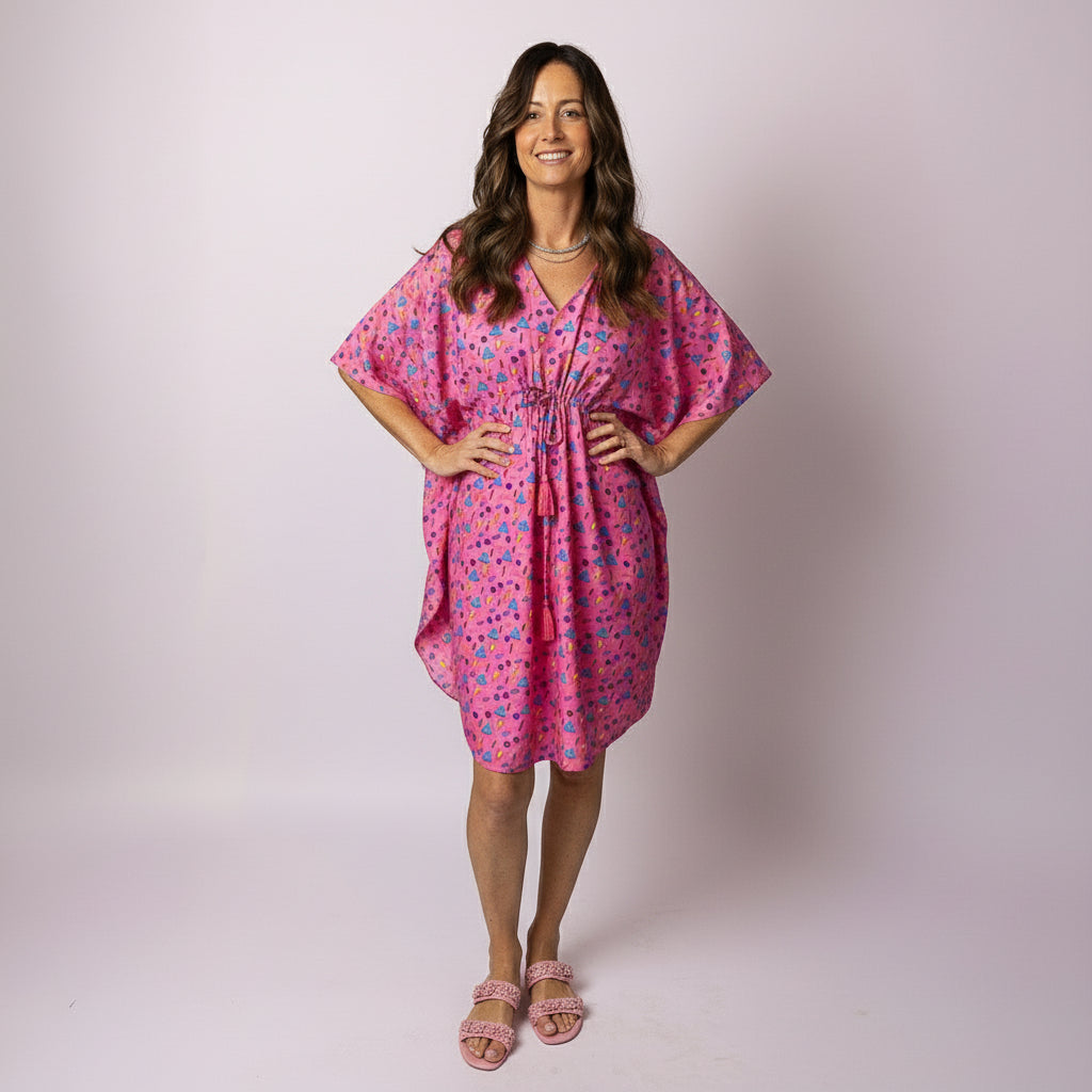 Woman wearing the Tropicool Retro Vibe Kaftan in pink, featuring a relaxed fit and colourful geometric print, perfect for Aussie summer events.
